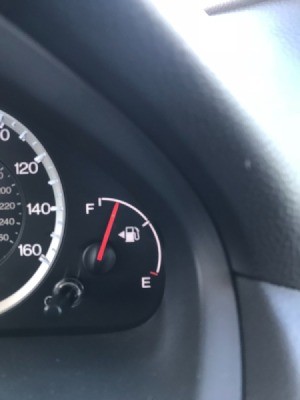 The fuel tank indicator in a car, with the arrow pointing to the side with the gas cap.