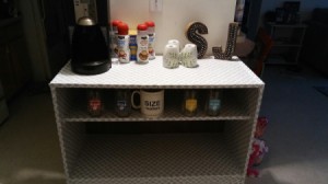 A white shelf with a coffee center and some condiments.