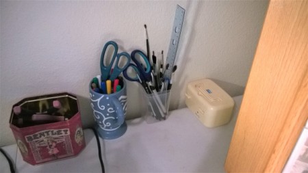 A clear plastic container with art supplies and office tools stored inside.
