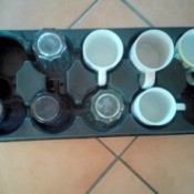 A plant tray being reused for coffee mugs and glassware.