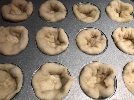 risen dough in muffing tins