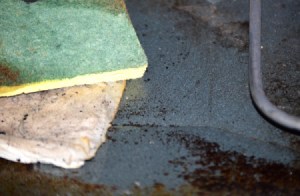 A dirty oven with wet paper towels and a scrubby sponge.