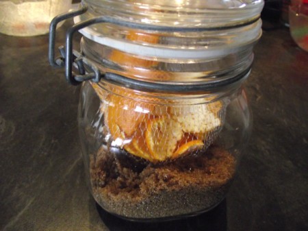 Orange peels inside a jar of brown sugar.