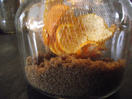 Orange peels inside a jar of brown sugar.