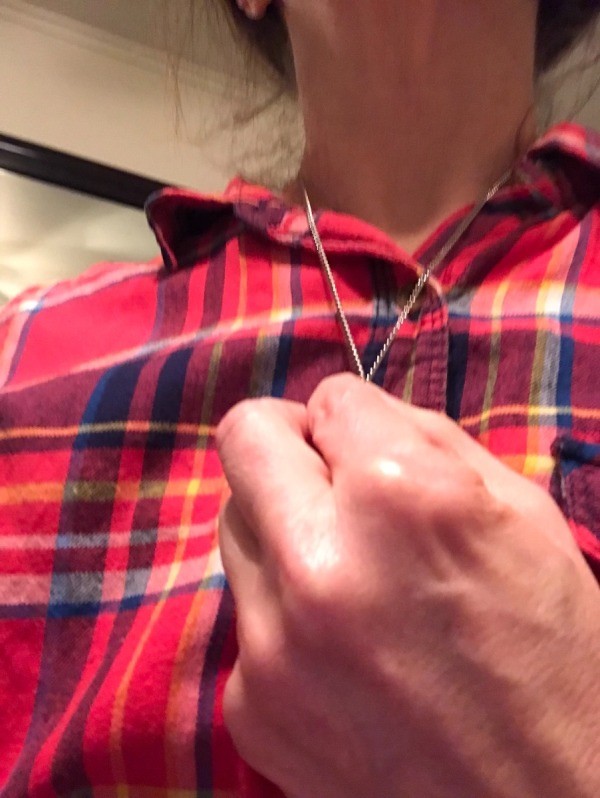 Pinching a chain necklace to temporarily shorten it.