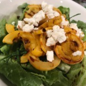 Roasted Delicata Squash on salad with cheese in bowl