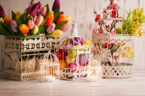 White wire birdcages filled with easter eggs and tulips.