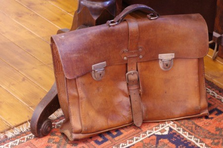 Worn leather bag on a area rug.