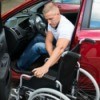 A disabled man moving from his car into a wheelchair.
