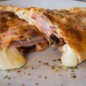 A ham and cheese calzone with melted cheese.