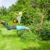 A man falling comically into bushes with his wheelbarrow in the air.