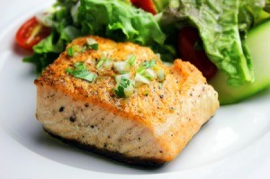 Salmon with fresh greens on a white plate.
