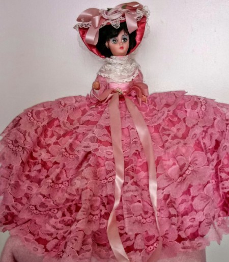 Identifying and Value of a Vintage Doll - small plastic doll wearing a ruffled dark pink dress and hat