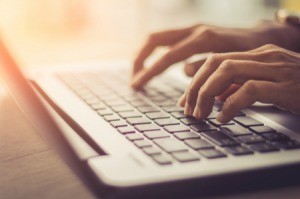 A pair of hands using a laptop computer.