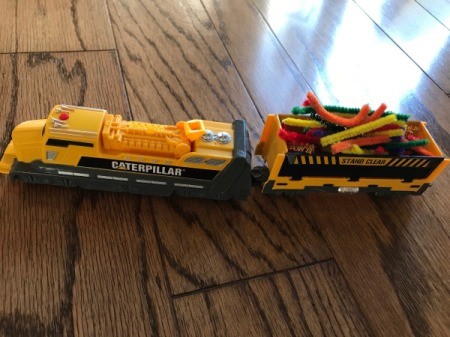 A toy train with cargo of colored pipe cleaners.