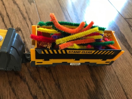 A toy train with cargo of colored pipe cleaners.