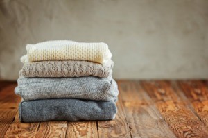 Stack of sweaters on a wood floor.