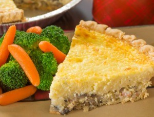 A slice crabmeat pie with a side of steamed broccoli and carrots.