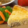 A slice crabmeat pie with a side of steamed broccoli and carrots.