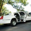White limo parked on a tree lined street with the back door opened.