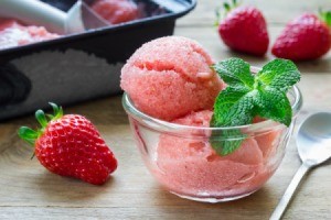 Homemade strawberry sorbet in a glass bowl with a sprig of mint.