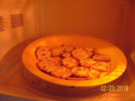 A plate of crackers in the microwave becoming crispy.
