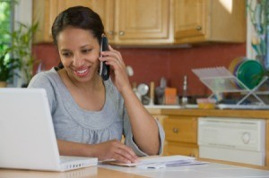 Woman sitting in front of computer calling phone company to resolve bill