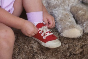 Little girl tying her red shoes