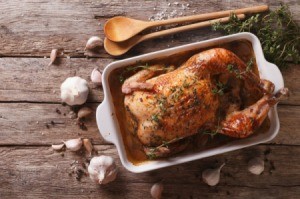 Whole roasted chicken in a pan surrounded with garlic.