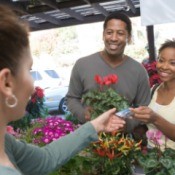 Couple at farmers market purchasing flowers with a debit card.