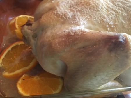 Baked chicken on cookie sheet with orange pieces