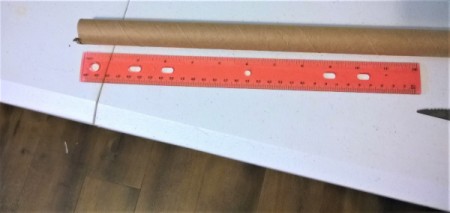 A tube being cut to about a foot length to extend a broom handle.