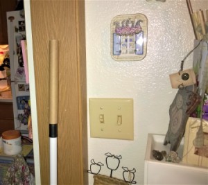A short broom handle being extended with a cardboard tube.