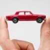 Hand holding a small red matchbox car.