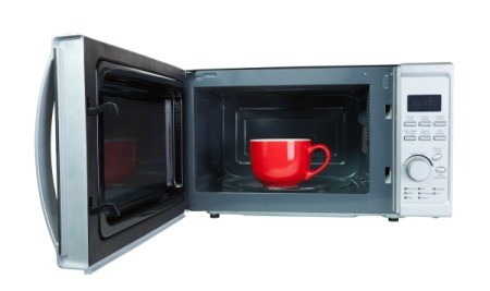 Red mug inside an open microwave.