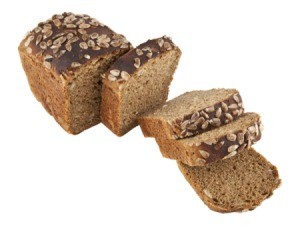 Loaf of Whole Wheat Oatmeal Quickbread partially sliced on a white background.