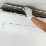 Person lifting off the ac filter on a wall air conditioning unit.