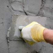 Person applying Stucco to a wall.