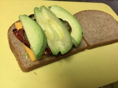 sliced avocado, cheese and roasted veggies on bread