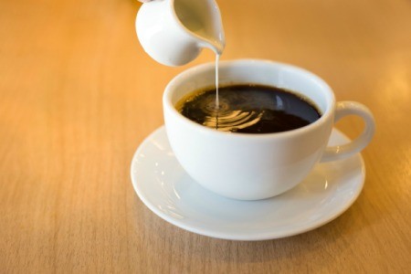 Cream being poured into a cup of coffee.