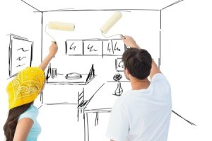 Man and woman with paint rollers pretending to paint a drawing of a room.