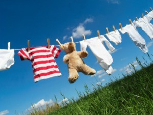 Clothes and a teddybear drying on the line on a clear day.