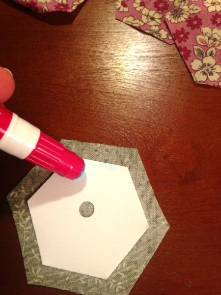 English Paper Pieced Hexagons - apply glue to one side of the template that has been placed on the wrong side of the fabric