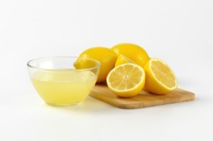 Lemon juice in a bowl and cutting board with fresh lemons on it.
