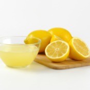 Lemon juice in a bowl and cutting board with fresh lemons on it.