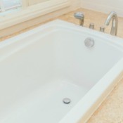 Clean white built in bathtub surrounded by sand colored tiles.