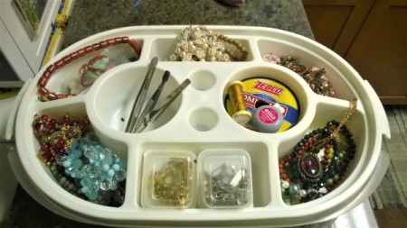 An old Tupperware container with several sections filled with jewelry findings.
