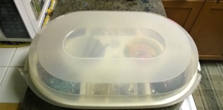 Closed Tupperware container with jewelry findings stored inside.