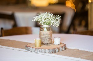 Mason jar wrapped with Jute rope filled with Babies Breath flowers on a table.