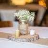 Mason jar wrapped with Jute rope filled with Babies Breath flowers on a table.